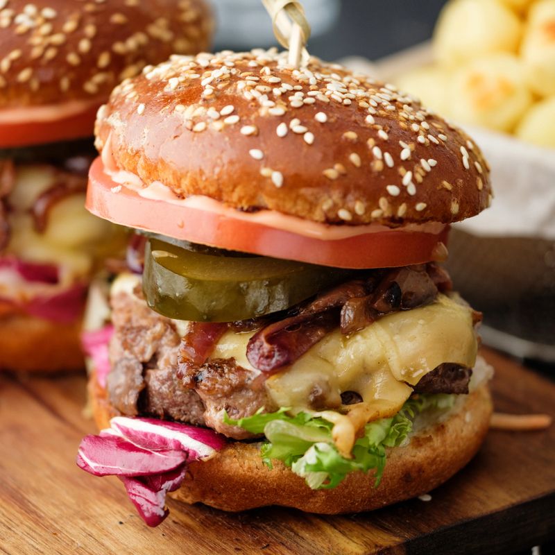 Closeup of Homemade delicious juicy burger with beef, cheese, tomato and caramelized onion and potato balls
