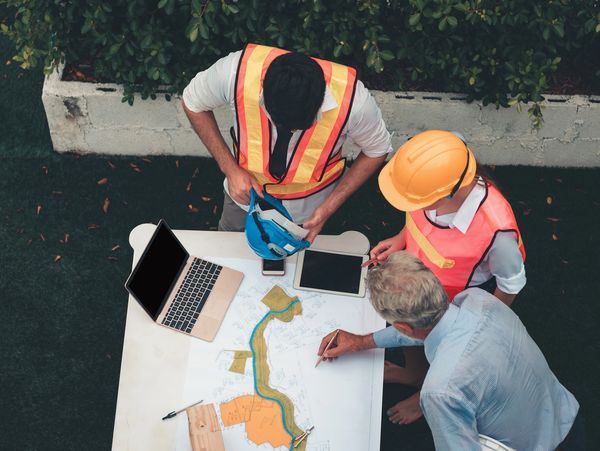 Three construction workers reviewing plans at a table.