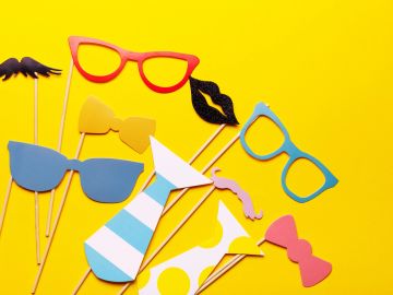 Colorful party props including glasses, ties, and lips on a yellow background.