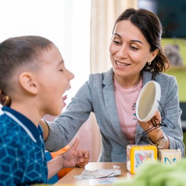 Speech therapist assisting a young boy with oral exercises.