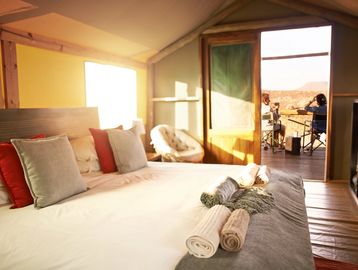 Bedroom tidied professionally with guests relaxing on balcony enjoying the view