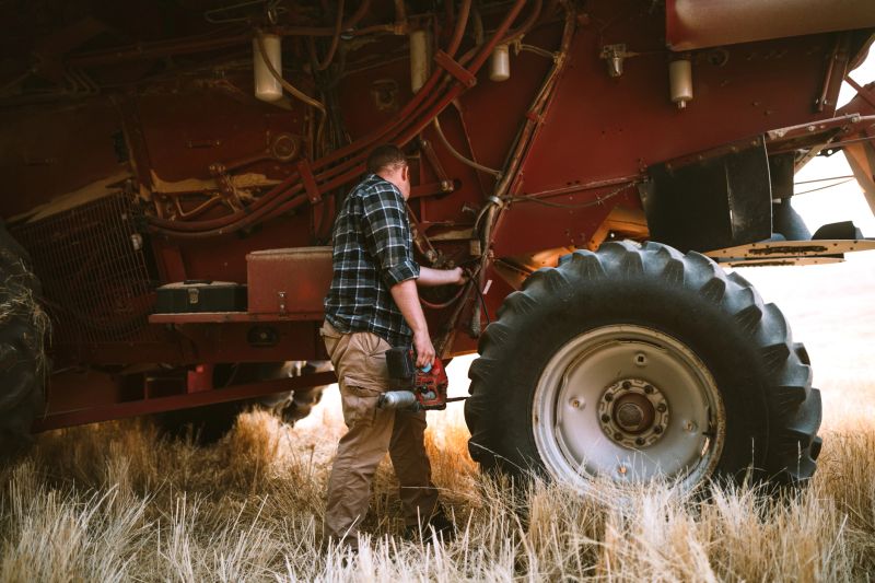 A wide angle image of rolling Idaho hills of golden wheat, a large combine grain harvester collecting ripe whole wheat berries.