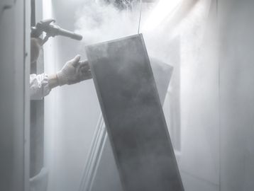Person spray painting a large object indoors.