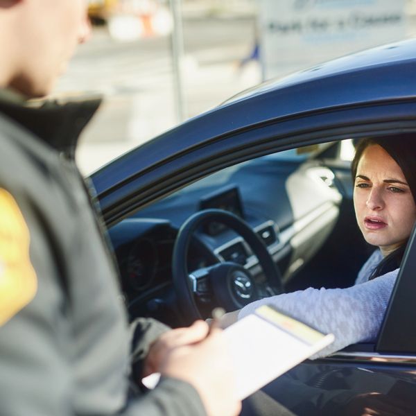 A white woman receiving a ticket from a police officer.