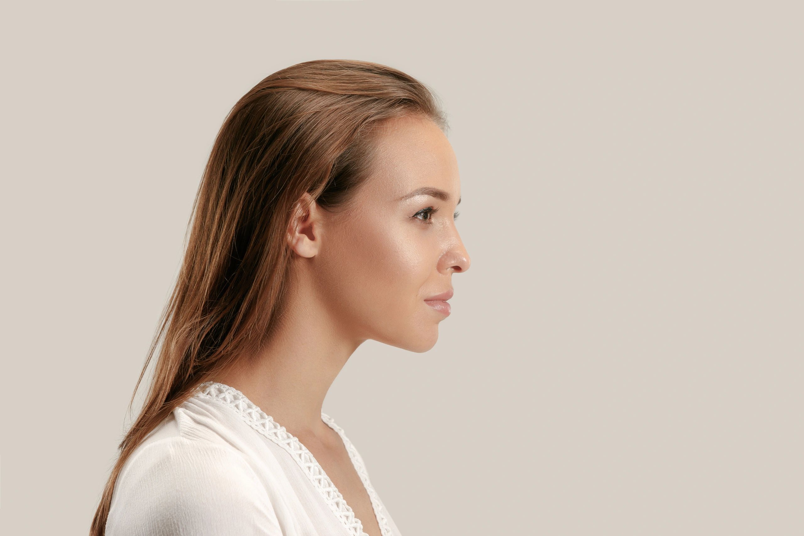 Profile view of a woman with soft, natural lip shape against a warm beige background