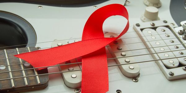 Red ribbon on guitar strings symbolizing awareness and support.