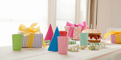 Birthday party table with cake, gifts, and decorations.