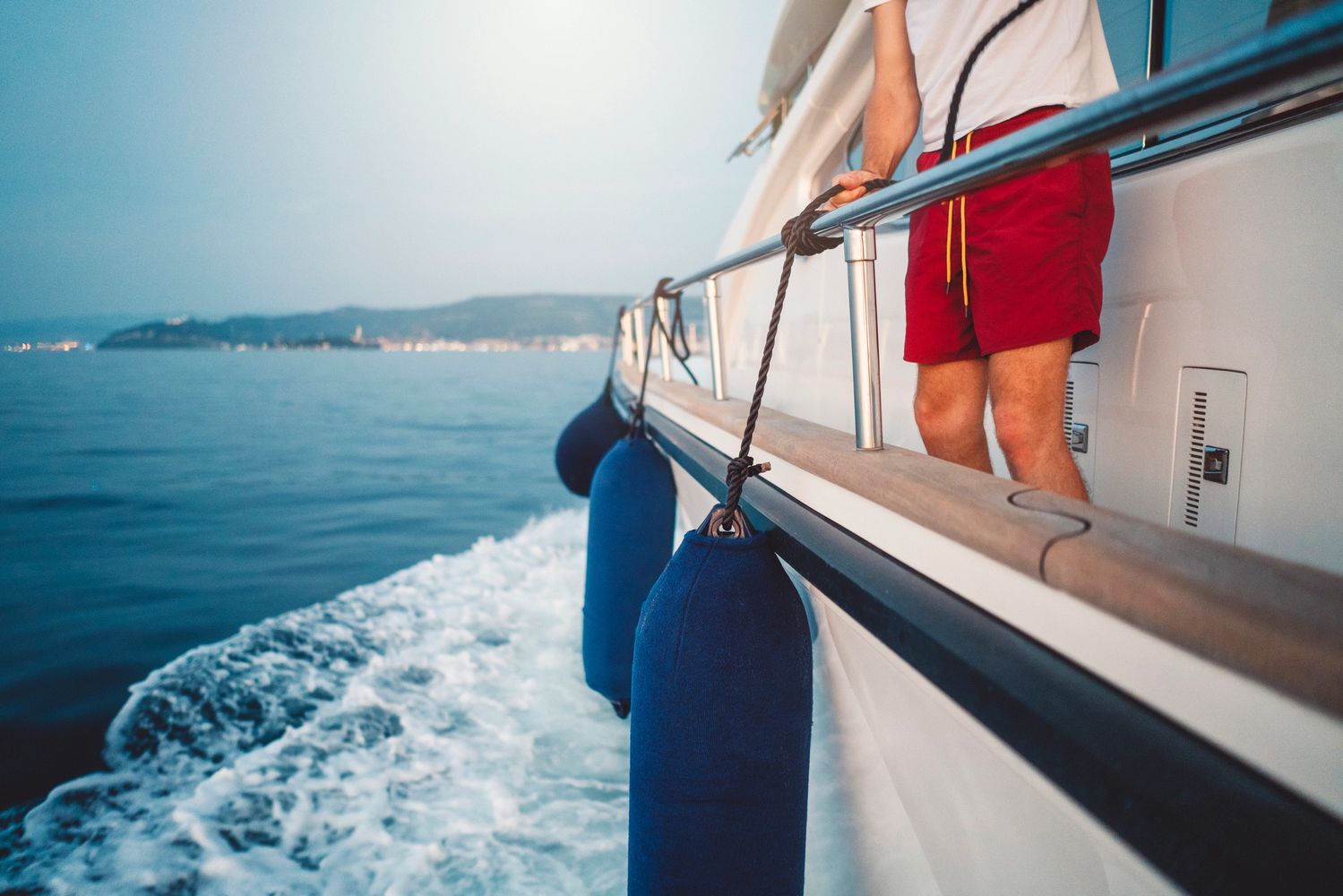 Person standing on a boat holding a rope with ocean in the background.