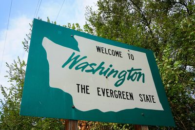 Welcome sign for Washington, the Evergreen State, surrounded by trees.
