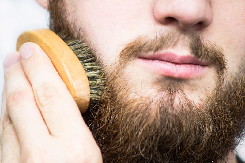 Hand of barber brushing beard. Barbershop customer,front view. Beard grooming tips for beginners. close-up