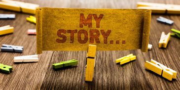 A clothespin holds a card reading 'MY STORY...' among scattered colorful clothespins.