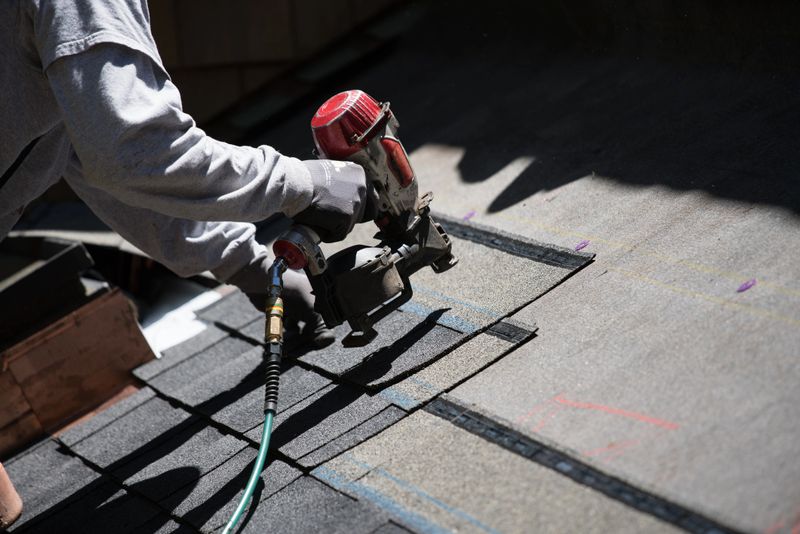 Installing new roof with  nail gun and shingles