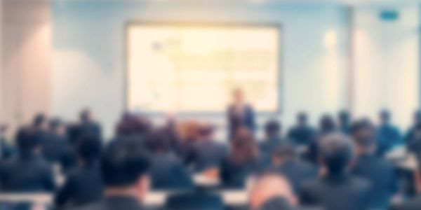 Blurred image of a presentation or lecture with an audience.