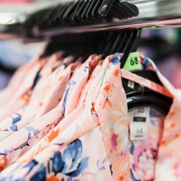 Floral patterned dresses hanging on a rack with size tags.