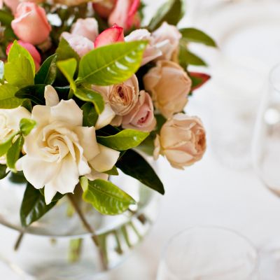 Elegant bouquet of pastel roses and green leaves in a glass vase.