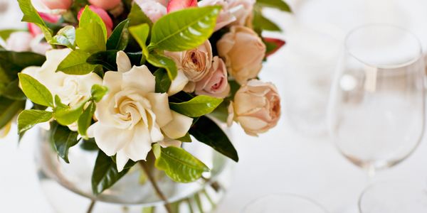 Elegant bouquet of white and pale pink roses with green leaves in a glass vase.
