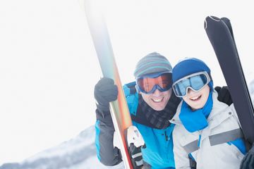 Smiling couple in ski gear holding skis.