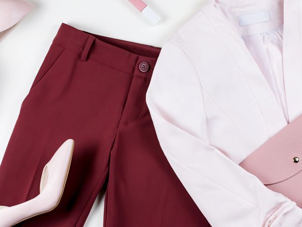 A stylish outfit with maroon pants and a light pink blazer.