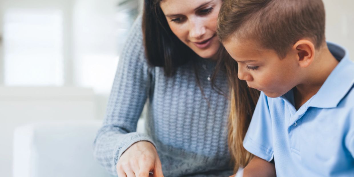 Woman helping boy with homework or reading.