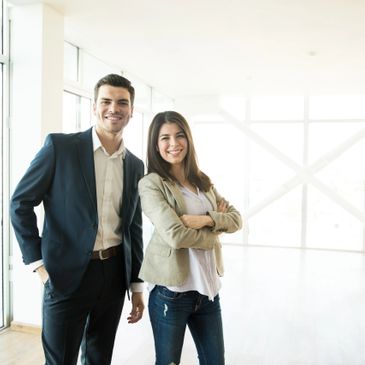 Two young professionals smiling confidently in a bright office space.