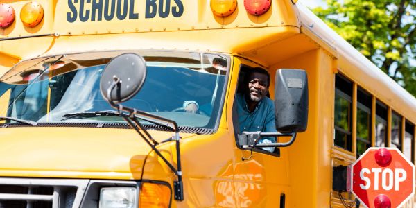 A smiling bus driver in a yellow school bus.