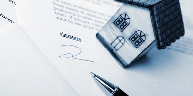 Contract signing with a house model and pen.