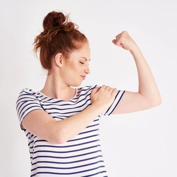 confident woman, flexing her bicep - representing strength, empowerment, and support