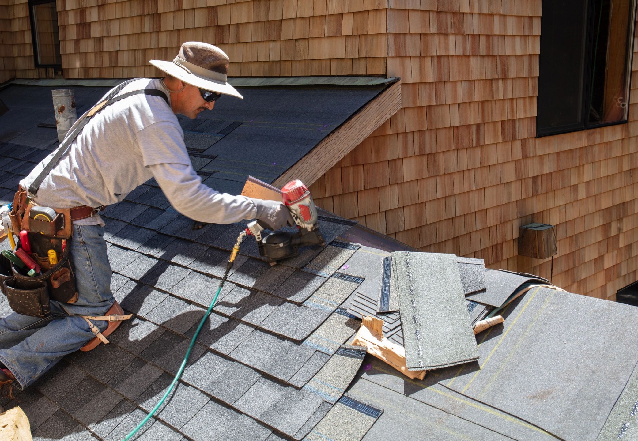 Roofer nailing shingles on new roof