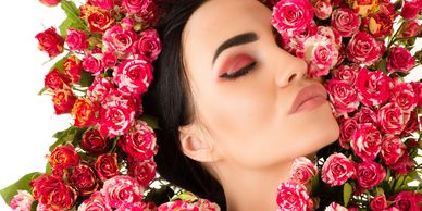 Woman with closed eyes surrounded by vibrant pink roses.