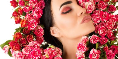Woman with closed eyes surrounded by vibrant pink roses.