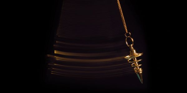 Golden pendulum swinging in the dark, creating light trails.