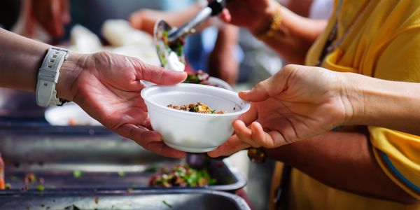 Person serving food in a white bowl to another person.
