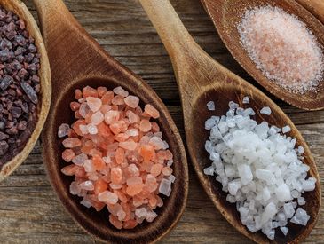 Different types of salt on wooden spoons.