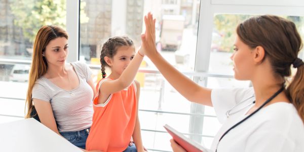 Child and doctor giving a high five during a checkup.