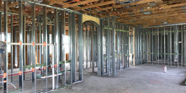 Interior of a building under construction with metal studs and wooden ceiling beams.