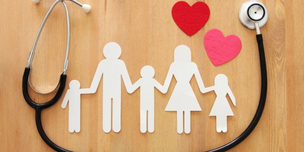 Paper cutout family with stethoscope and hearts.