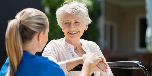 Caregiver and elderly woman sharing a moment outdoors.