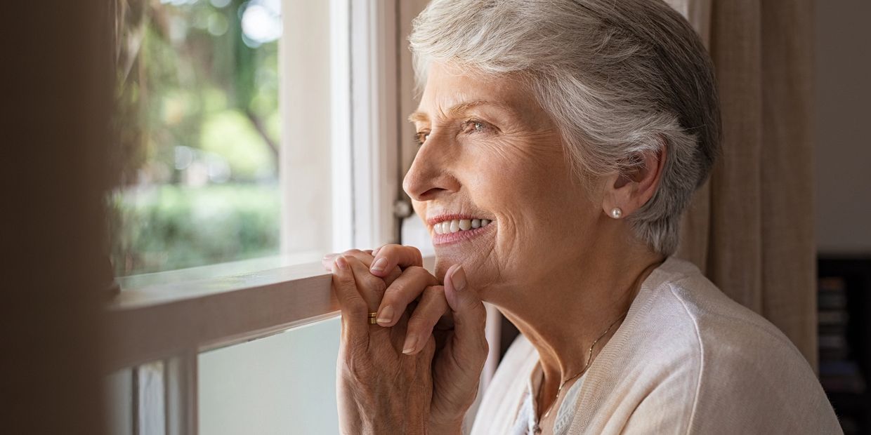 Elderly woman smiling while looking out a window