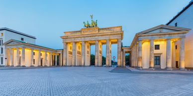The illuminated Brandenburg Gate in Berlin at dusk with clear skies.