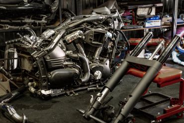 Disassembled motorcycle parts in a workshop with tools and equipment.