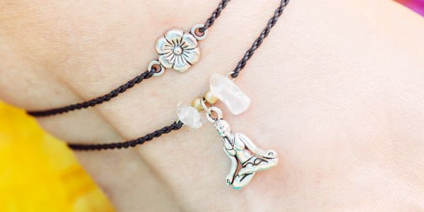 Black string bracelets with silver flower and meditating Buddha charms.