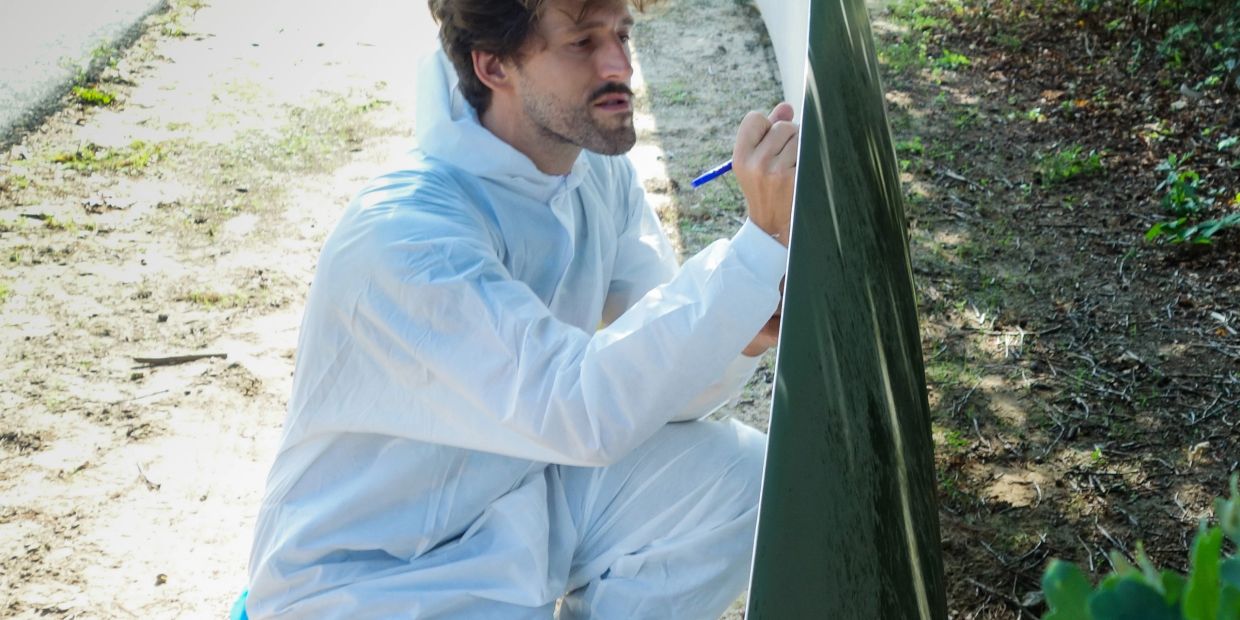 Forensic investigator examining evidence on a green surface.