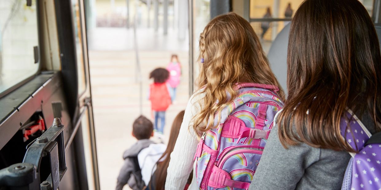 Children with backpacks boarding a school bus.