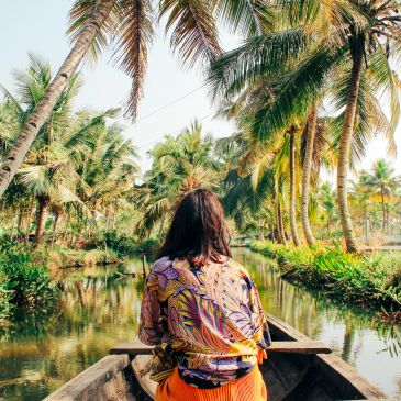 Person boating through tropical palm trees.