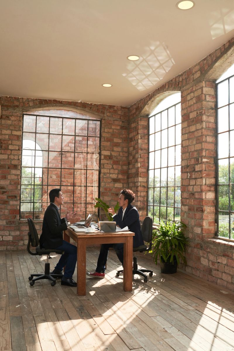 Vietnamese business executives talking at table in office with vintage brick walls