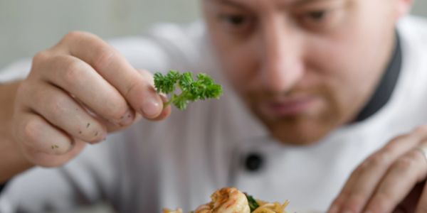 Chef delicately garnishing a dish with fresh herbs.