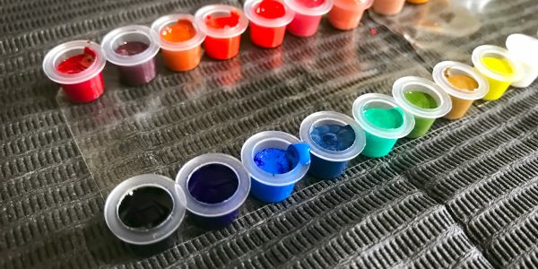 Small paint containers in a rainbow arrangement.