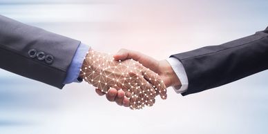 Two businesspeople shaking hands, with a digital network overlay on one hand.