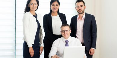 Four professionally dressed colleagues posing confidently in a bright office space.