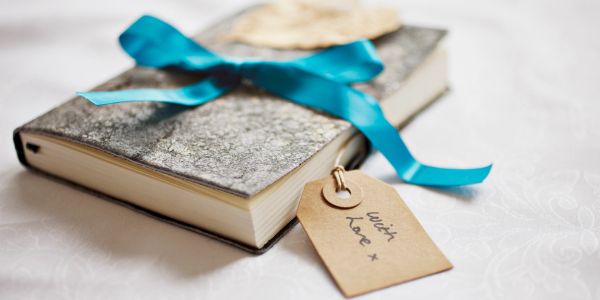 A book gift wrapped with a blue ribbon and a tag.
